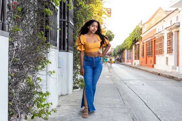 Modelo con top amarillo y jean caminando por una calle colonial