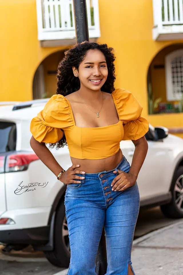 Modelo con top amarillo frente a una fachada amarilla