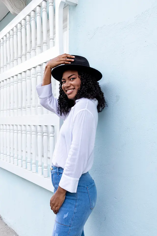 Modelo con sombrero negro contra una pared blanca