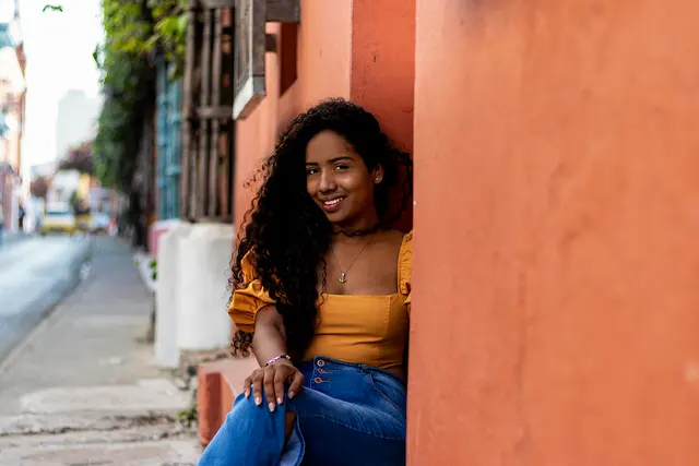 Modelo sentada contra una pared naranja