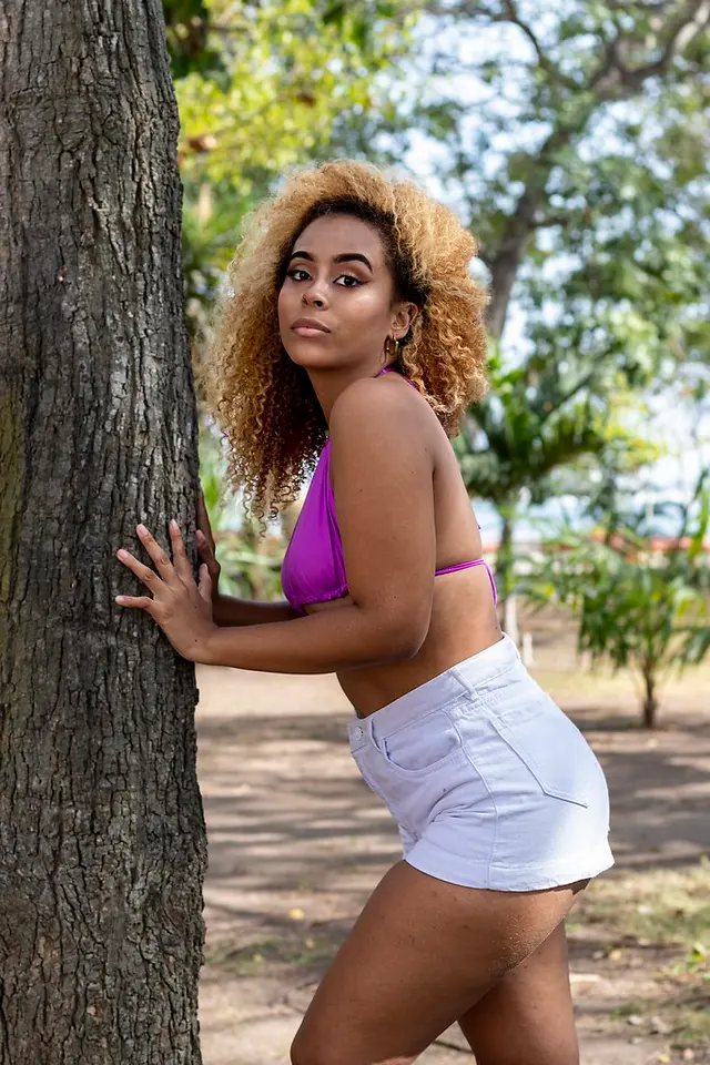Modelo de pelo rizado apoyada en un árbol